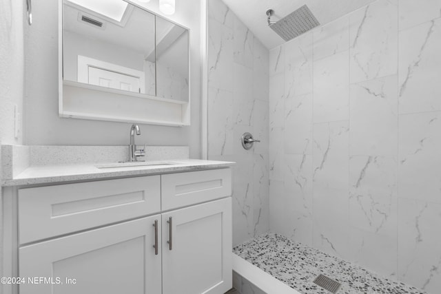 bathroom featuring a tile shower and vanity