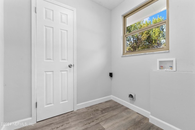 laundry area featuring electric dryer hookup, hookup for a washing machine, and light hardwood / wood-style flooring