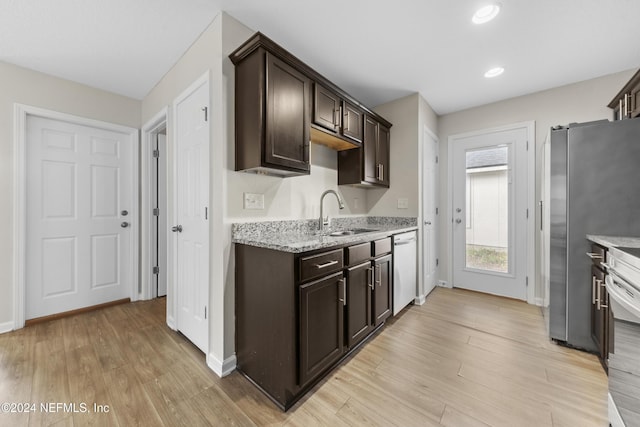 kitchen featuring dark brown cabinetry, light stone counters, light hardwood / wood-style flooring, and sink