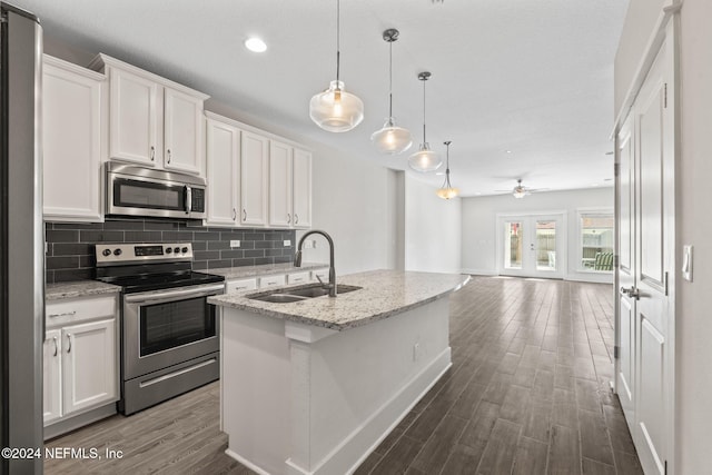 kitchen with white cabinets, stainless steel appliances, hanging light fixtures, and sink