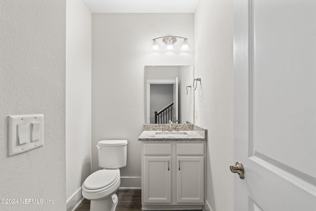 bathroom with hardwood / wood-style floors, vanity, and toilet