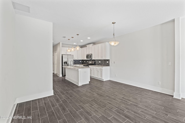 kitchen featuring hanging light fixtures, dark hardwood / wood-style floors, an island with sink, white cabinetry, and stainless steel appliances