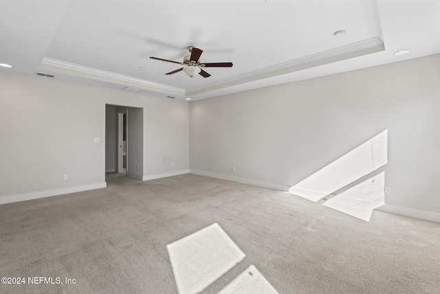 carpeted empty room featuring a raised ceiling, ceiling fan, and crown molding