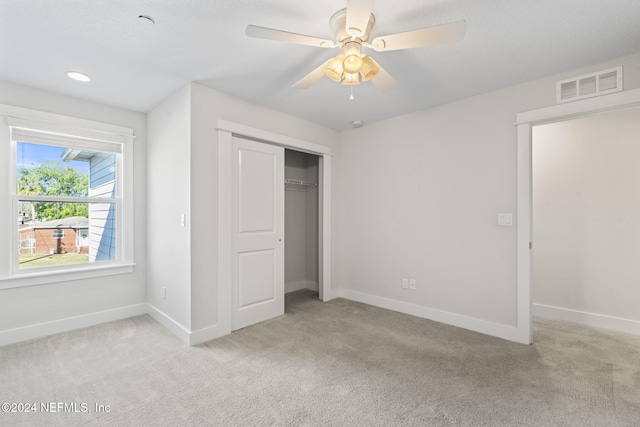 unfurnished bedroom featuring ceiling fan, a closet, and light carpet