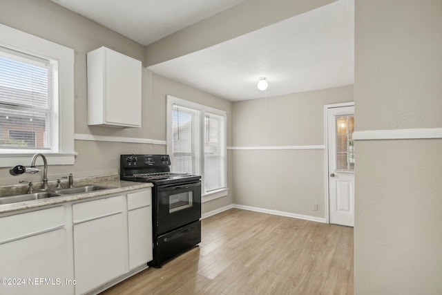 kitchen with black electric range, white cabinets, light hardwood / wood-style flooring, and sink