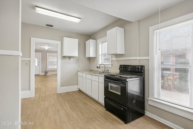 kitchen with black electric range, light hardwood / wood-style floors, white cabinets, and sink