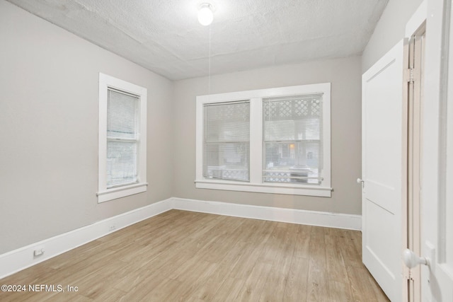 spare room with a textured ceiling and light wood-type flooring