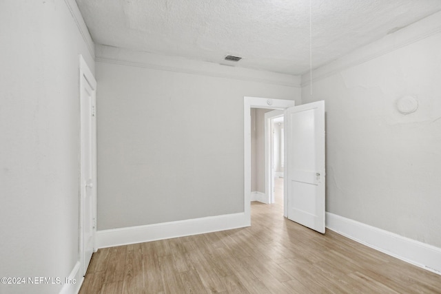 spare room with crown molding, light hardwood / wood-style flooring, and a textured ceiling