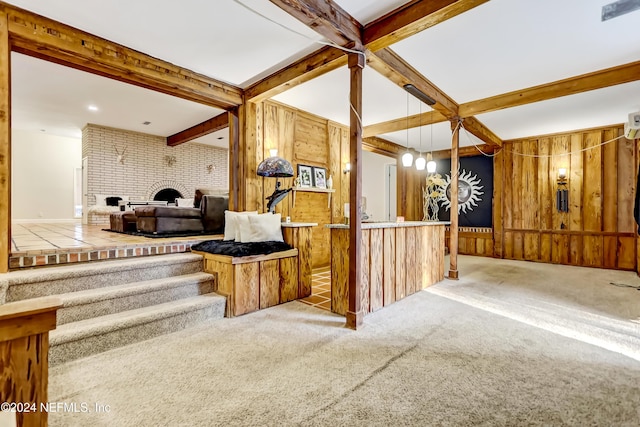 interior space with light carpet, wooden walls, a brick fireplace, and beamed ceiling