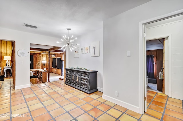 interior space featuring a notable chandelier, light tile patterned floors, and wooden walls