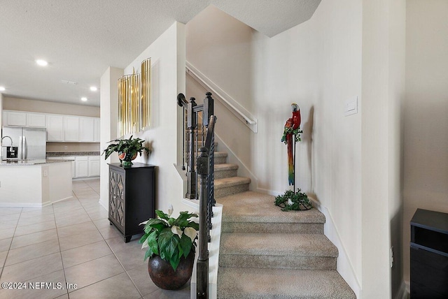 stairs featuring tile patterned flooring and a textured ceiling