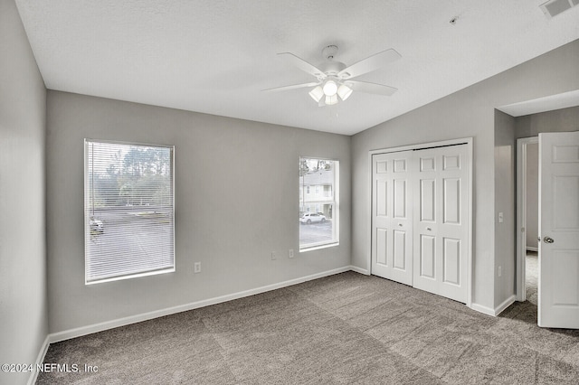 unfurnished bedroom with ceiling fan, a closet, carpet floors, and multiple windows