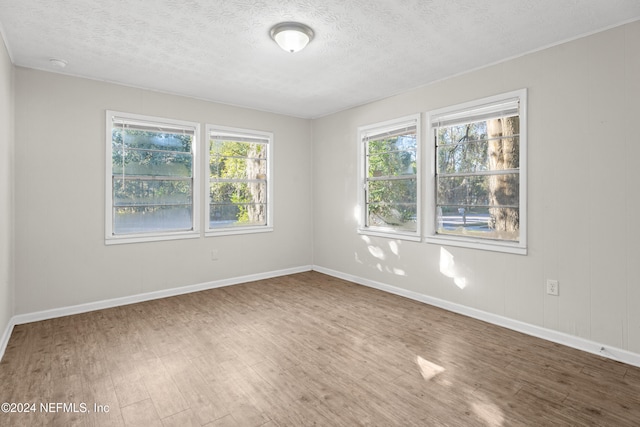 spare room with a textured ceiling and hardwood / wood-style flooring