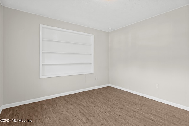 empty room with hardwood / wood-style flooring and built in shelves