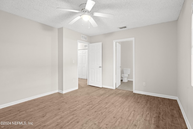 unfurnished bedroom featuring hardwood / wood-style floors, ceiling fan, a textured ceiling, and ensuite bath