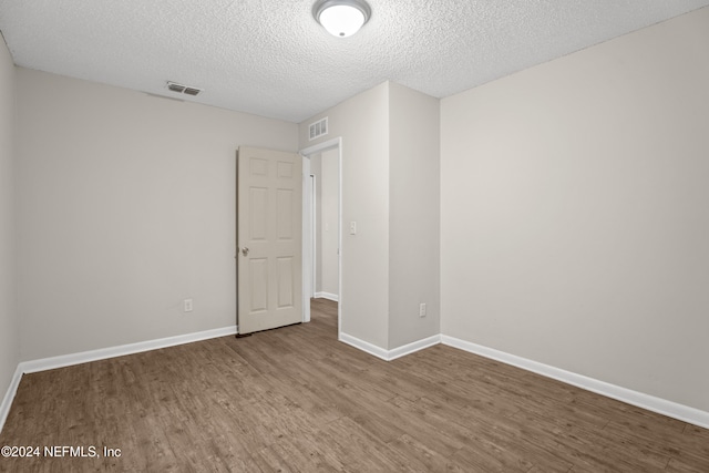 unfurnished room with a textured ceiling and hardwood / wood-style flooring