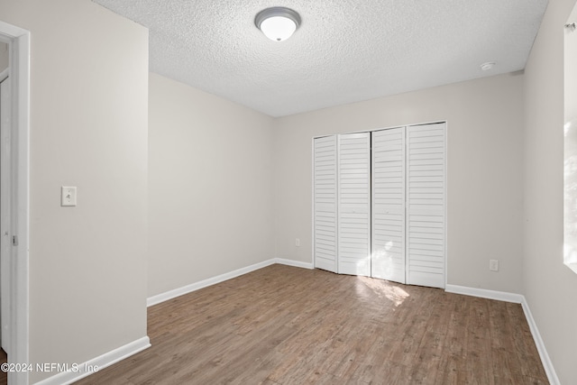 unfurnished bedroom with hardwood / wood-style floors, a textured ceiling, and a closet