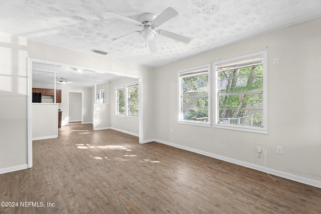 empty room with ceiling fan, dark hardwood / wood-style flooring, and a textured ceiling