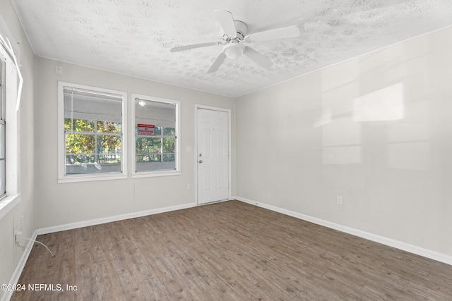 empty room with ceiling fan, dark hardwood / wood-style flooring, and a textured ceiling