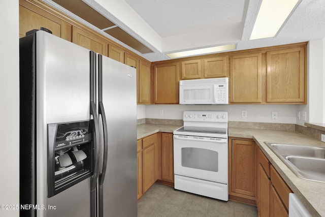 kitchen with white appliances, sink, and a textured ceiling