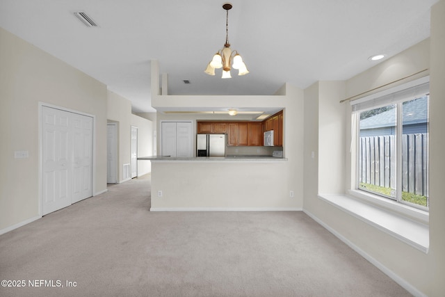 unfurnished living room featuring light carpet and a chandelier