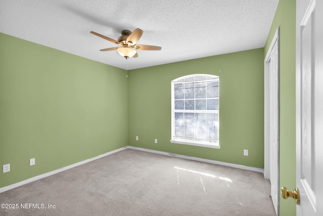 spare room with ceiling fan, light colored carpet, and a textured ceiling