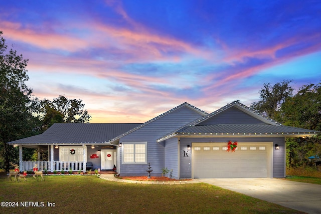 view of front of home with covered porch, a garage, and a lawn