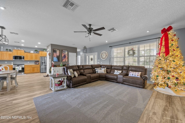 living room featuring a textured ceiling, light hardwood / wood-style flooring, and ceiling fan