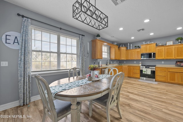 dining space featuring sink, a textured ceiling, and light wood-type flooring