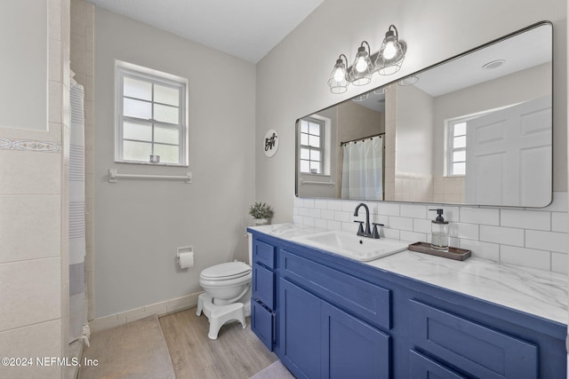 bathroom featuring plenty of natural light, vanity, hardwood / wood-style floors, and toilet