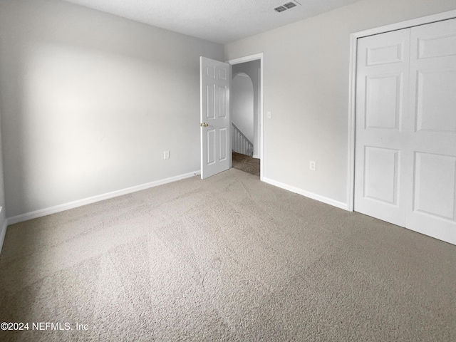 unfurnished bedroom featuring a closet, carpet floors, and a textured ceiling