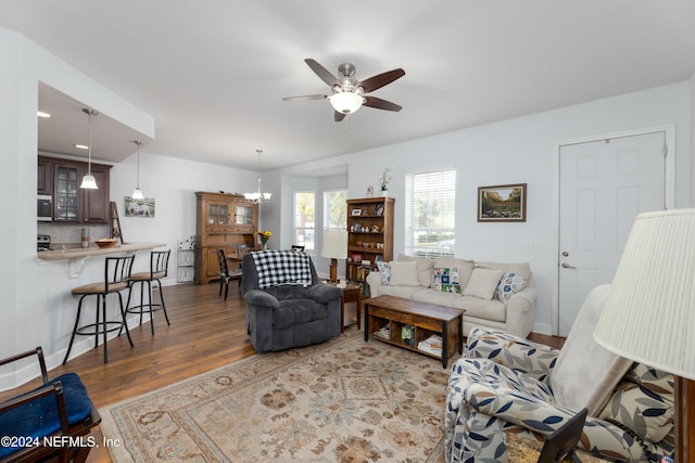 living room with ceiling fan with notable chandelier and dark hardwood / wood-style floors