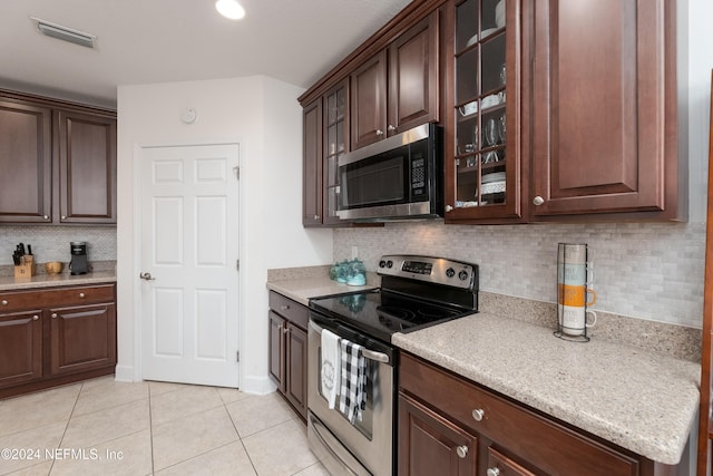 kitchen with tasteful backsplash, dark brown cabinetry, light tile patterned floors, and appliances with stainless steel finishes