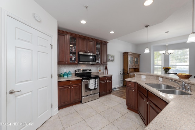 kitchen with an inviting chandelier, hanging light fixtures, sink, decorative backsplash, and appliances with stainless steel finishes