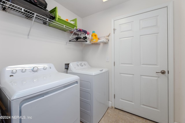 clothes washing area with washing machine and dryer and light tile patterned floors