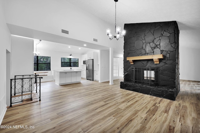 living room with a stone fireplace, sink, high vaulted ceiling, and light hardwood / wood-style floors