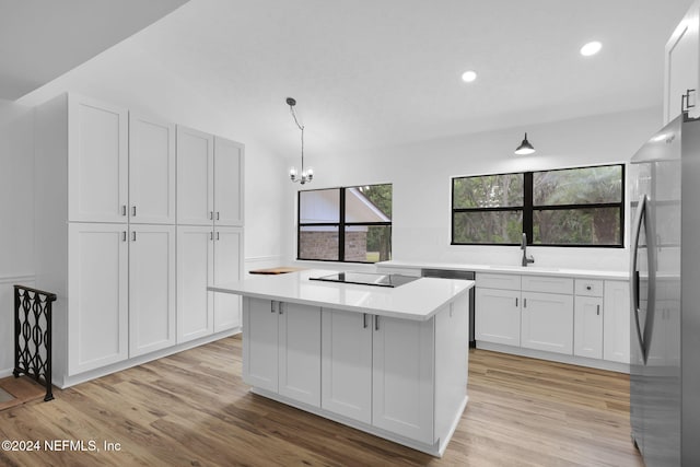 kitchen featuring a center island, stainless steel fridge, light hardwood / wood-style floors, decorative light fixtures, and white cabinets