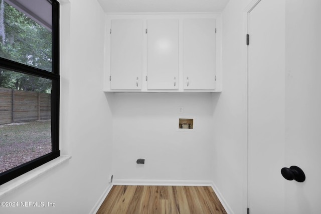 washroom with cabinets, washer hookup, and light hardwood / wood-style flooring