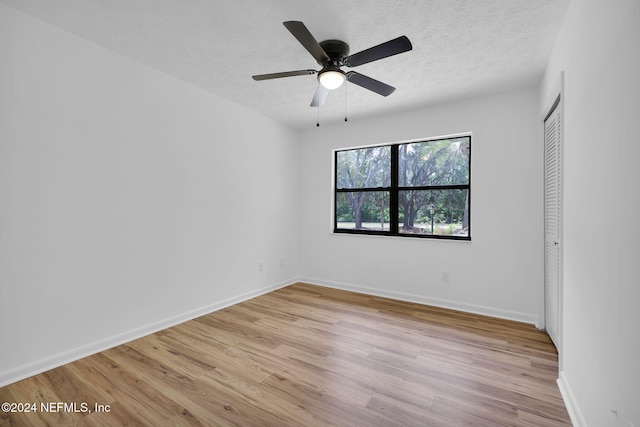 unfurnished room featuring a textured ceiling, light wood-type flooring, and ceiling fan