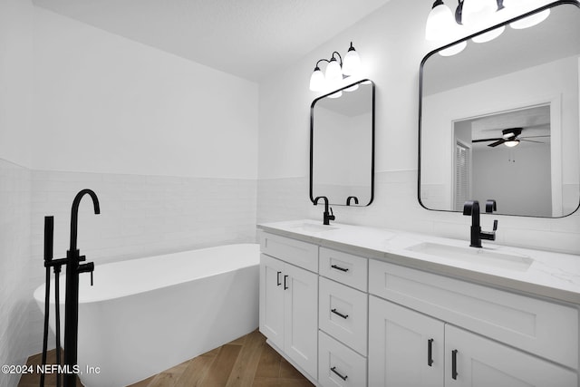 bathroom with vanity, hardwood / wood-style flooring, ceiling fan, a tub to relax in, and tile walls