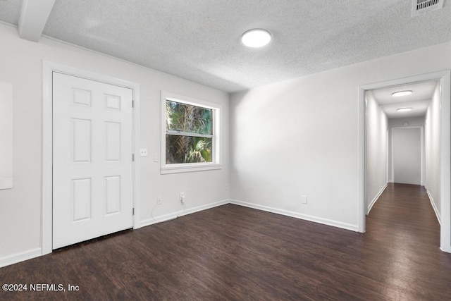 spare room featuring a textured ceiling and dark wood-type flooring