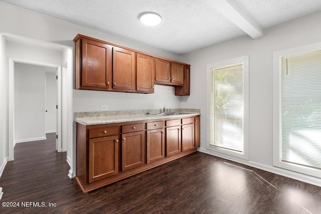 kitchen with beamed ceiling, a textured ceiling, dark wood-type flooring, and sink