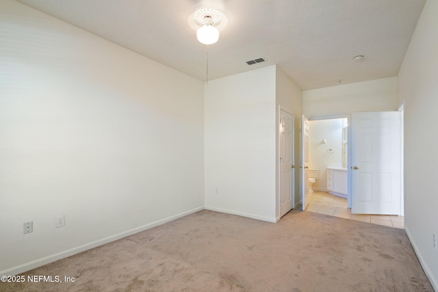 unfurnished bedroom with ensuite bath and light colored carpet