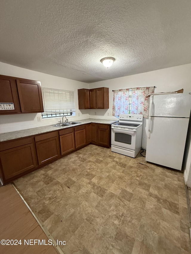 kitchen featuring a textured ceiling, sink, and white appliances