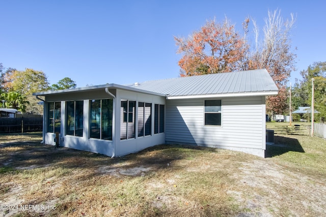 rear view of house featuring a sunroom and a lawn