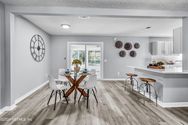 dining room featuring a textured ceiling and light hardwood / wood-style flooring