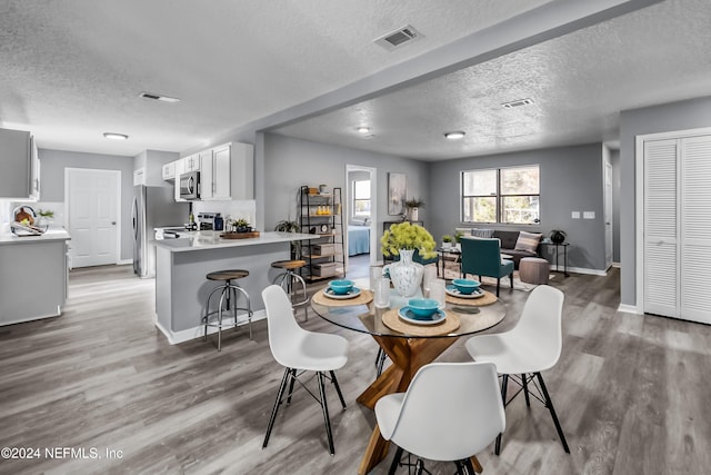 dining space featuring hardwood / wood-style floors and a textured ceiling