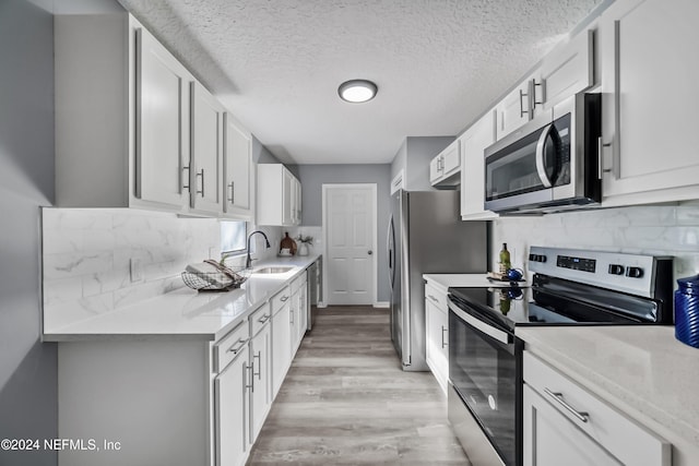 kitchen featuring white cabinetry, sink, light wood-type flooring, and appliances with stainless steel finishes