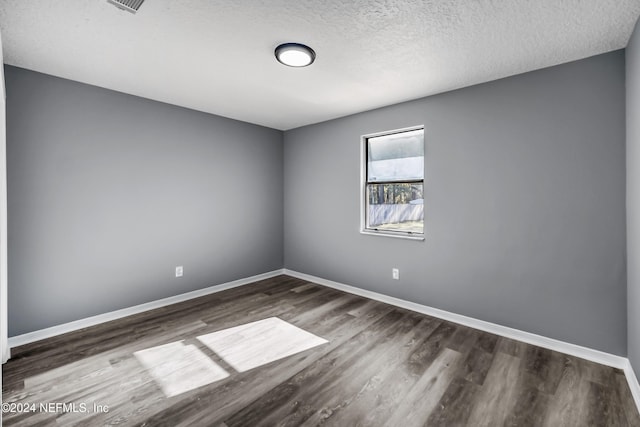 empty room with dark wood-type flooring and a textured ceiling