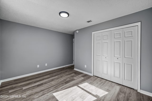 unfurnished bedroom with hardwood / wood-style floors, a textured ceiling, and a closet